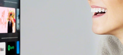 Femeie care controlează TV-ul cu „mâinile libere”, folosind vocea