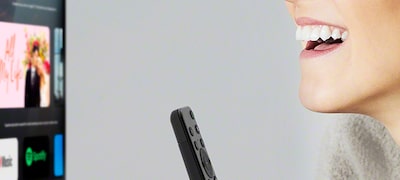 Prim-plan cu o femeie controlând vocal televizorul de la distanță