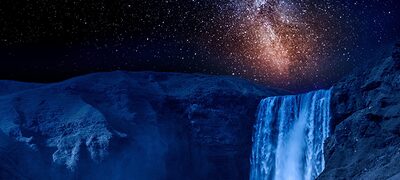 Prim-plan cu o cascadă pe timp de noapte, cu stele iluminate în galaxia de pe cer