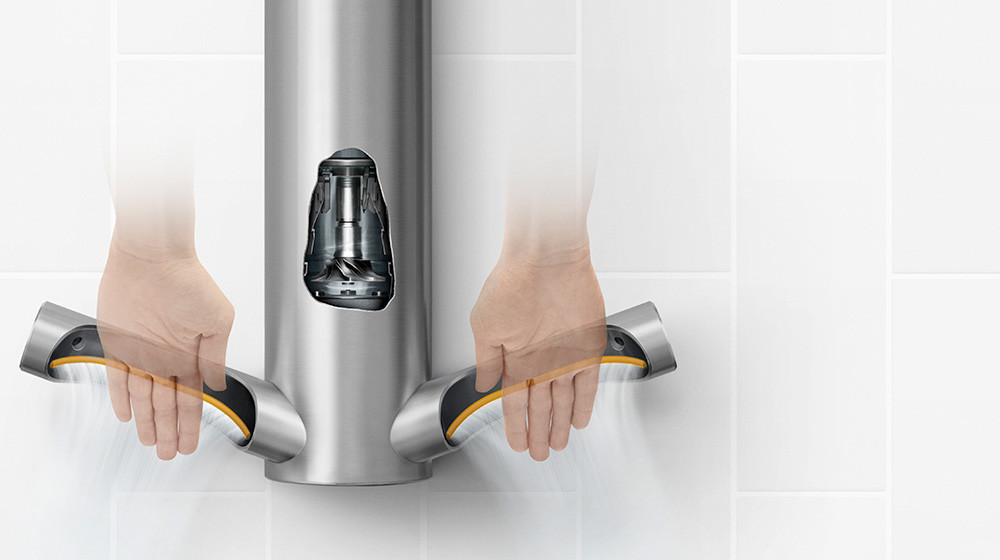 Model care își usucă mâinile sub uscătorul de mâini Dyson Airblade 9kJ. 