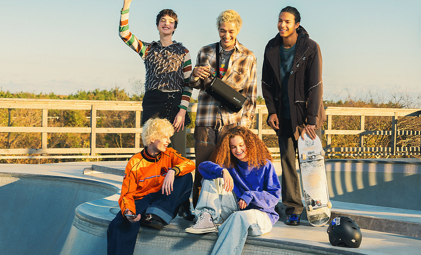 Cinci persoane într-un parc de skateboard, adunate în jurul unei persoane care ține boxa ULT FIELD 5 peste umăr