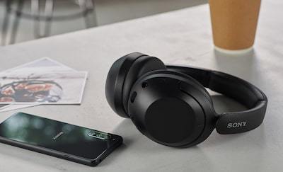 WH-XB910N headphones in black, on a table alongside a coffee and a smartphone