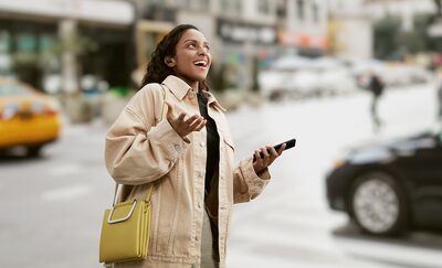 Femeie purtând căștile LinkBuds S în timp ce se plimbă prin oraș și vorbește la smartphone