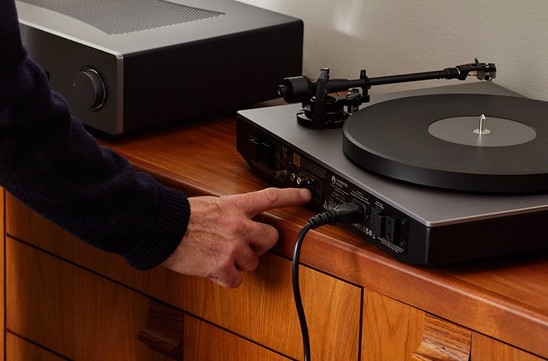 Person pressing button on back of alva tt v2 turntable