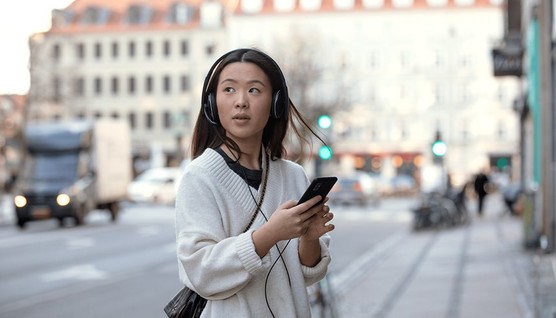 adapt-100---young-woman-on-sidewalk-with-headphones-on